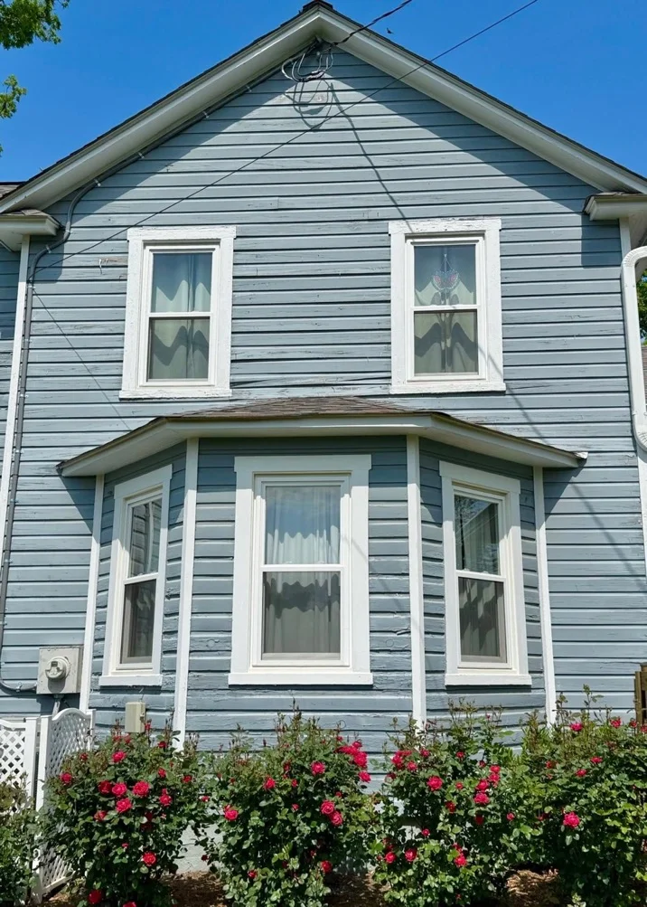 Exterior of the side of a house with drab light green paint