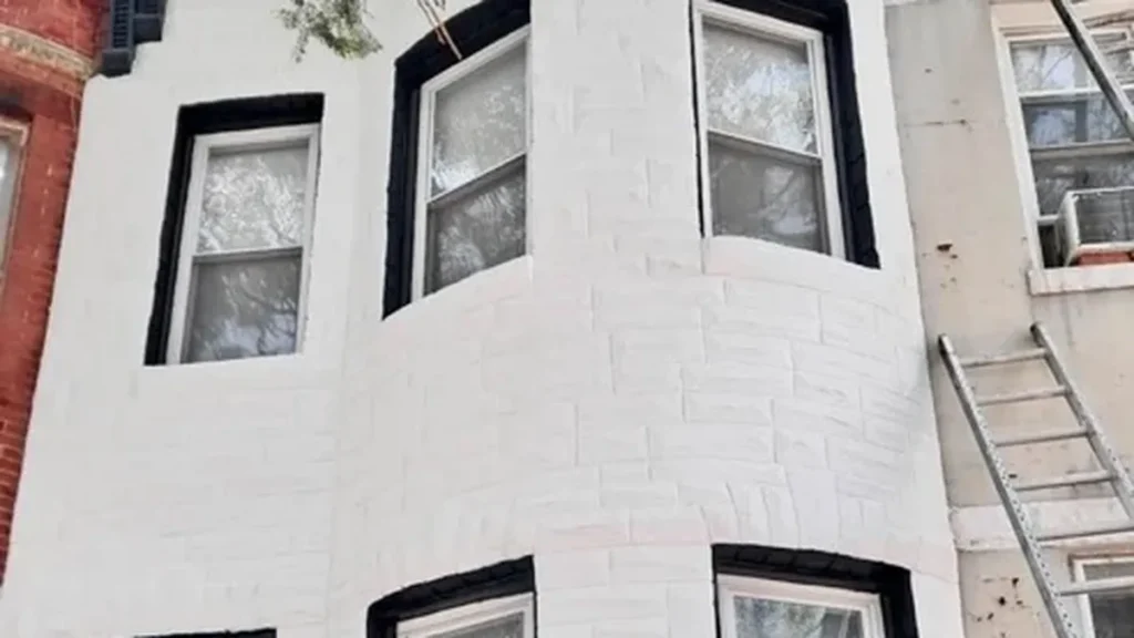 White-painted brick townhome facade with a curved bay and black window trim