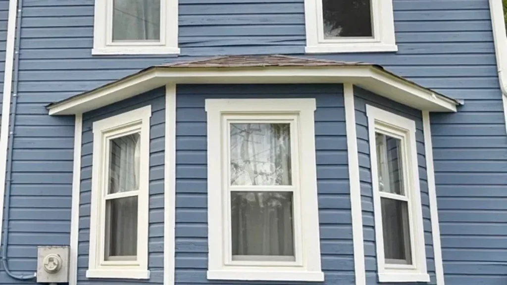 Freshly painted blue siding with white trim around a bay window on a Maryland home